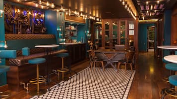 A bar area with a checkered floor, bar stools, and a seating area with a table and chairs.