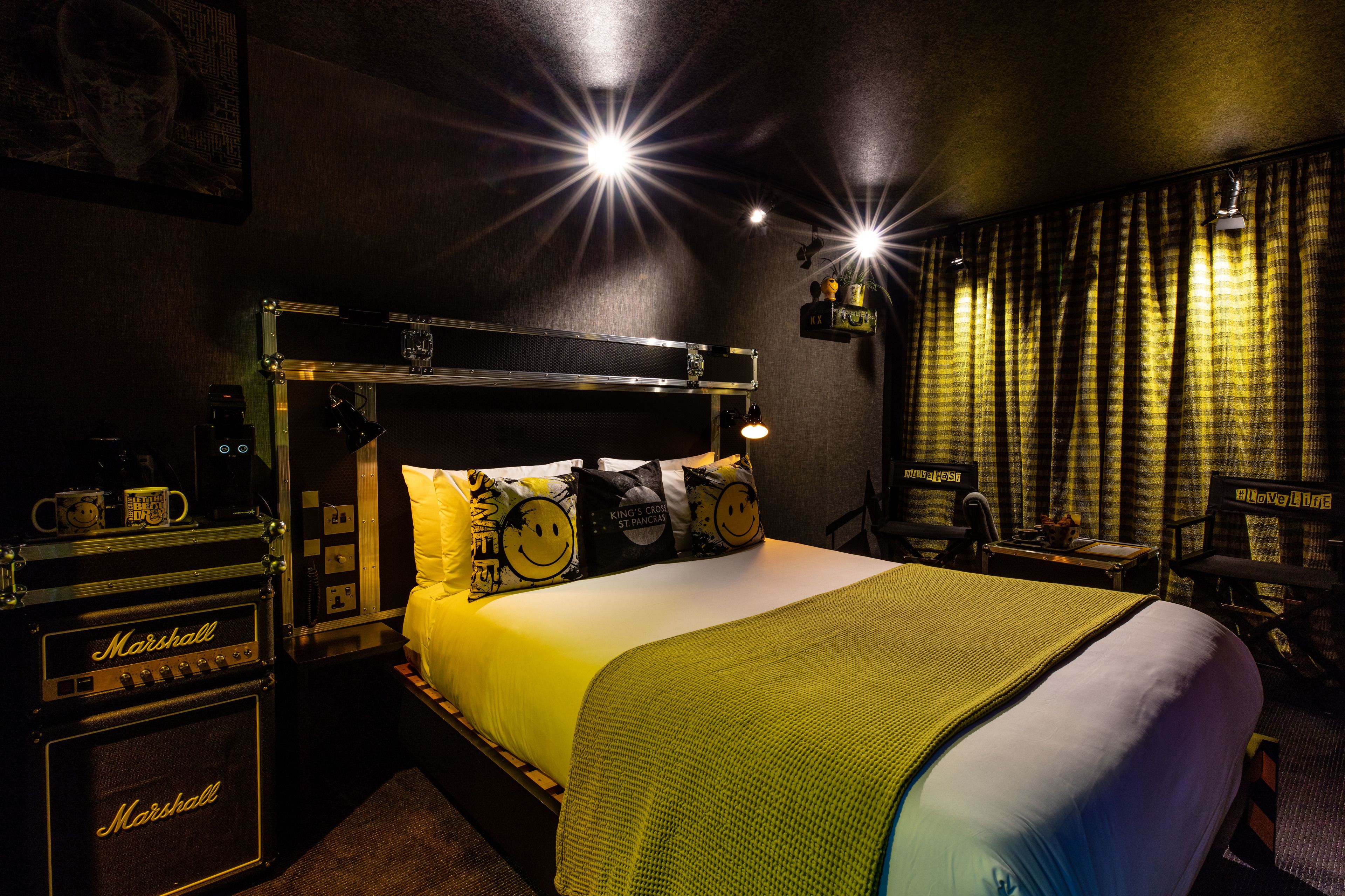 Una camera d'albergo con un letto, un amplificatore Marshall e un letto a scomparsa.