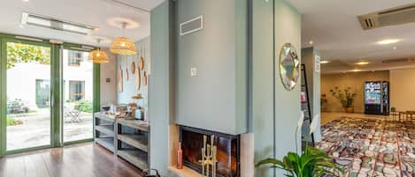 Una sala moderna con chimenea, un comedor con mesa y sillas, y un suelo estampado.