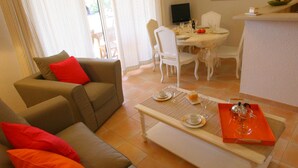 A living room with a sofa, a coffee table, and a dining area with a table and chairs.