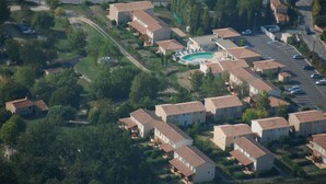 An aerial view of a residential area with multiple two-story houses, a swimming pool, and a parking lot.