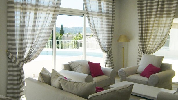 A living room with two sofas, a lamp, and a view of a pool and mountains.