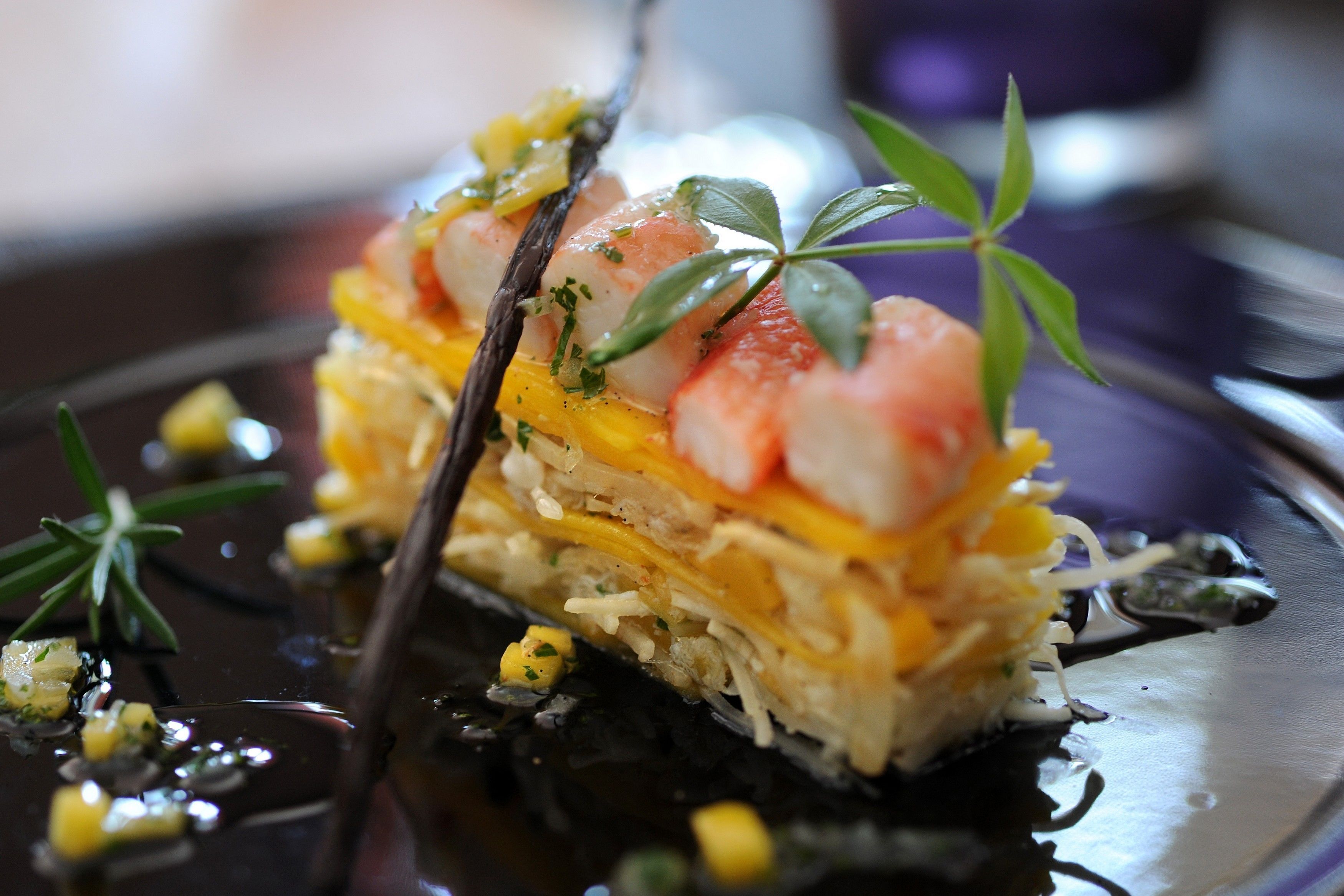 A close-up of a gourmet dish with seafood and vegetables on a plate.