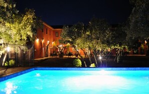 A nighttime swimming pool area with a building in the background.