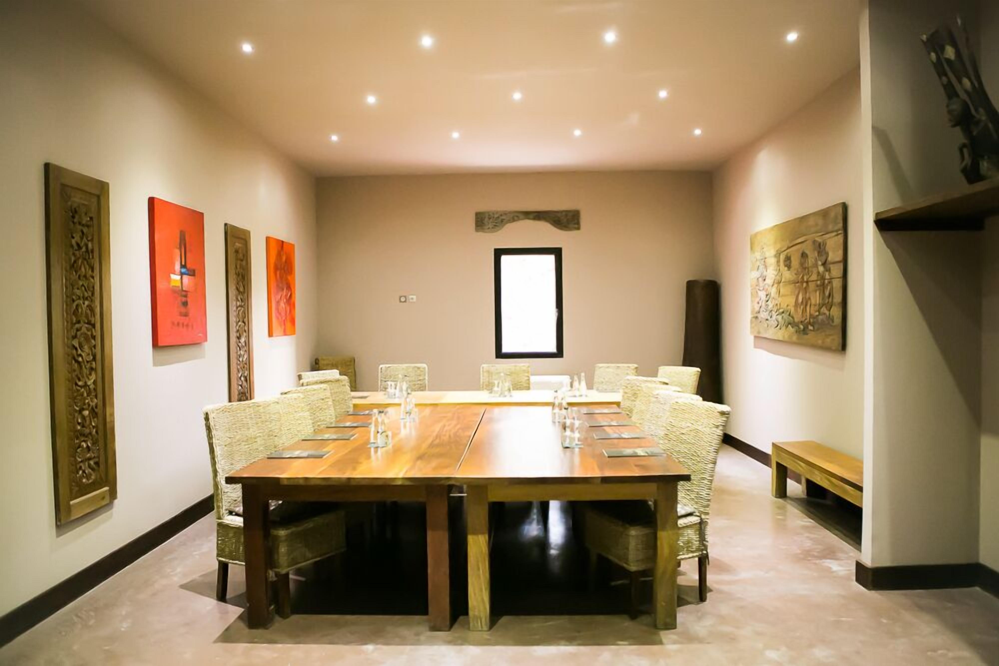 A conference room with a long wooden table, wicker chairs, and artwork on the walls.