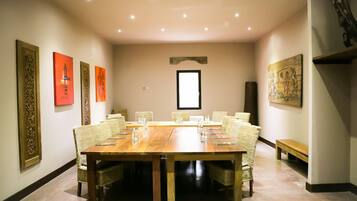 A conference room with a long wooden table, wicker chairs, and artwork on the walls.
