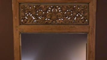 A bedroom with a large bed, a wooden headboard with intricate carvings, and a carpeted floor.