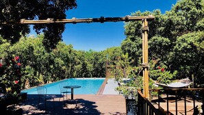A wooden deck with a pool, surrounded by lush greenery and trees. - Hôtel restaurant spa Disini Montpellier Est, The Originals Relais (Castries)