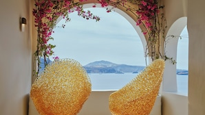 Dos sillas doradas con vista a un cuerpo de agua y una montaña al fondo.