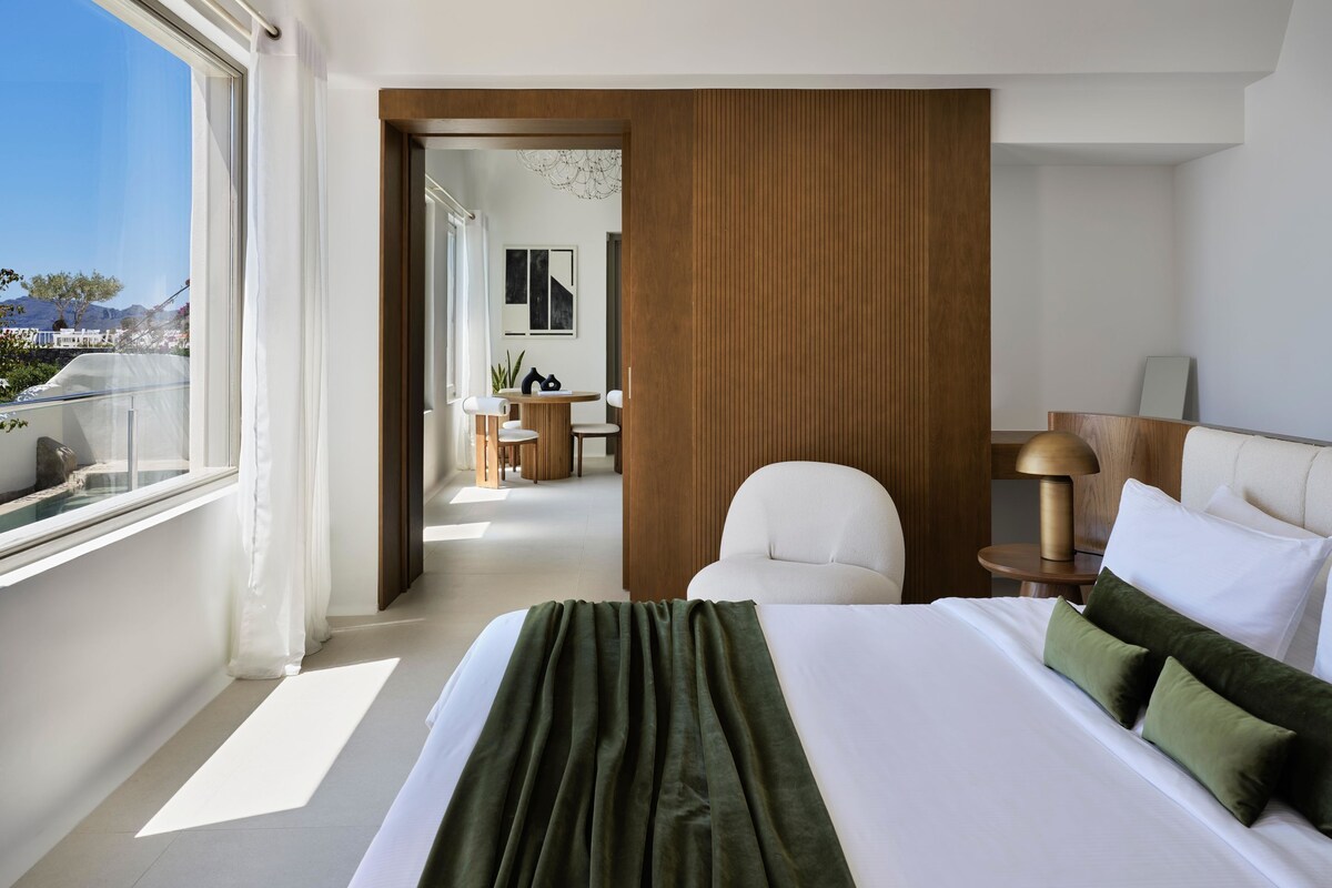 Habitación de hotel moderna con una cama grande, un escritorio y vistas al exterior.