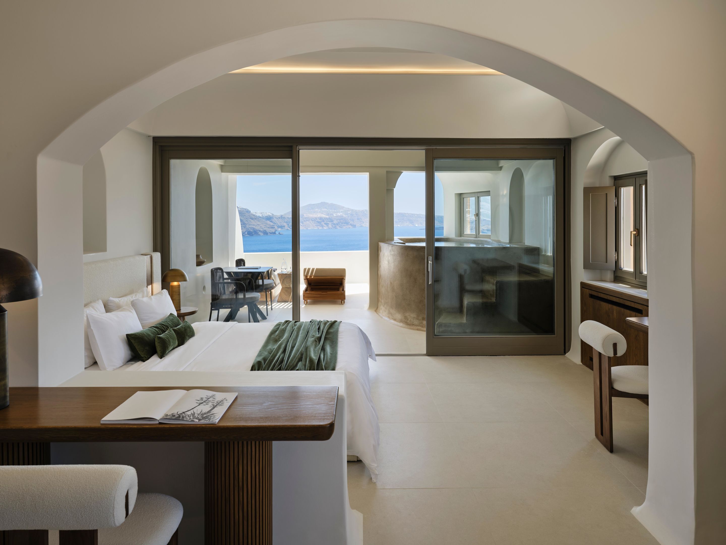 Una habitación de hotel moderna con una cama grande, un escritorio y un balcón con vistas al mar.