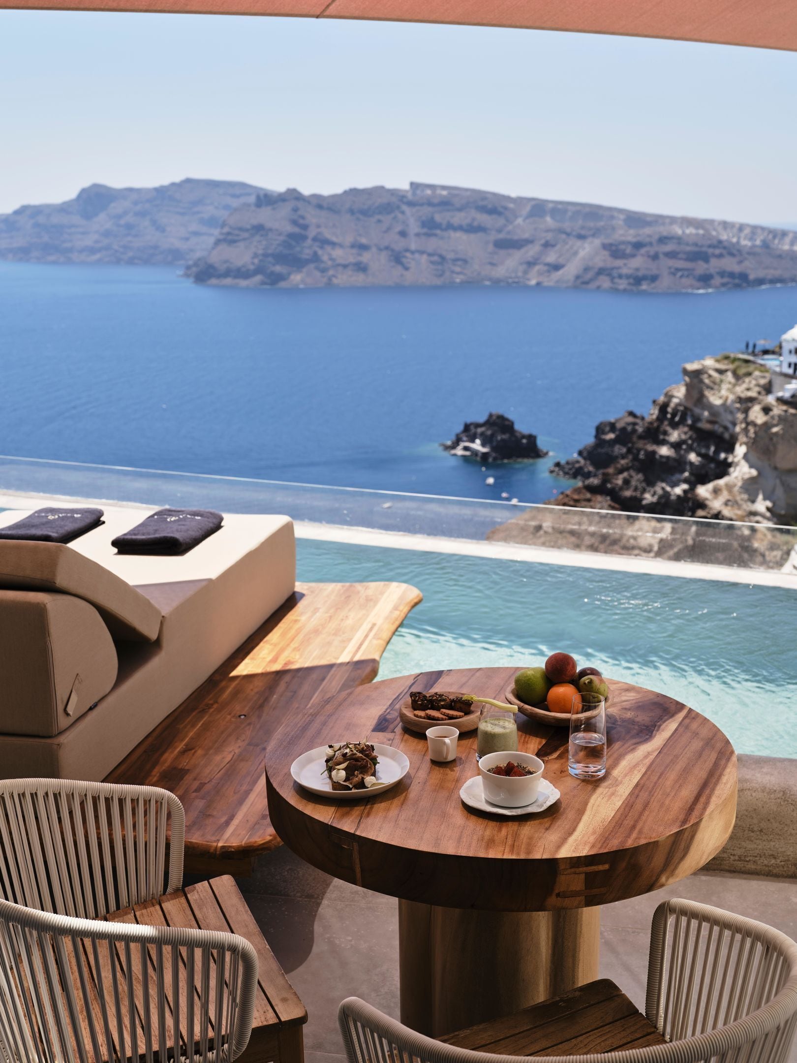 A wooden table with a view of the sea and rocky cliffs.