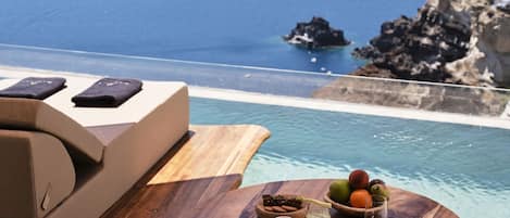 A wooden table with a view of the sea and rocky cliffs.
