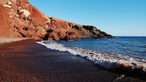Una platja amb un penya-segada rocosa i ones oceàniques.