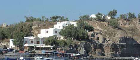 A coastal town with white buildings, a rocky hillside, and boats docked at the harbor.