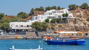 Un hotel a la costa amb edificis blancs, una platja i embarcacions a l'aigua.