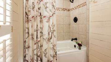 Un baño con ducha, bañera y ventana con persianas.
