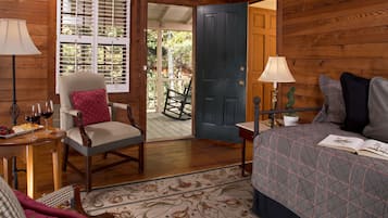 Una habitación acogedora con cama, una silla, una mesa con copas de vino y una puerta que da al exterior.