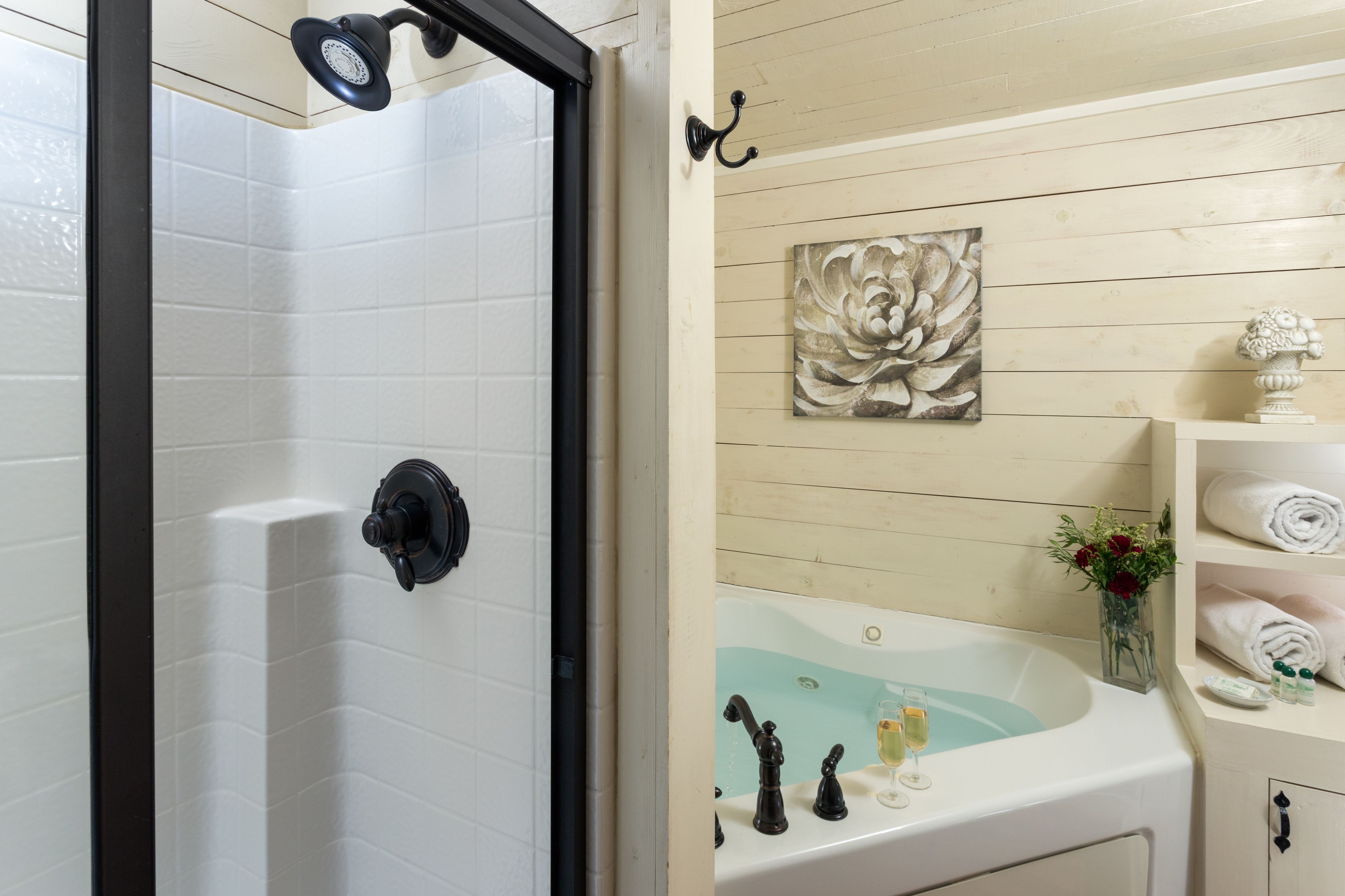 A bathroom with a shower, a bathtub, and a sink. There is a decorative flower vase on the sink and a towel rack on the wall.