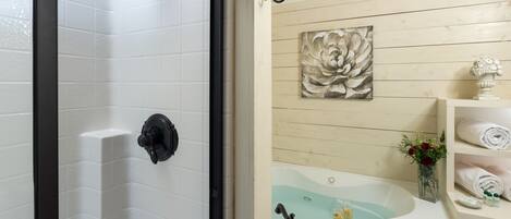 A bathroom with a shower, a bathtub, and a sink. There is a decorative flower vase on the sink and a towel rack on the wall.