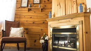 A wooden-paneled room with a fireplace, a chair, and a vase with flowers.