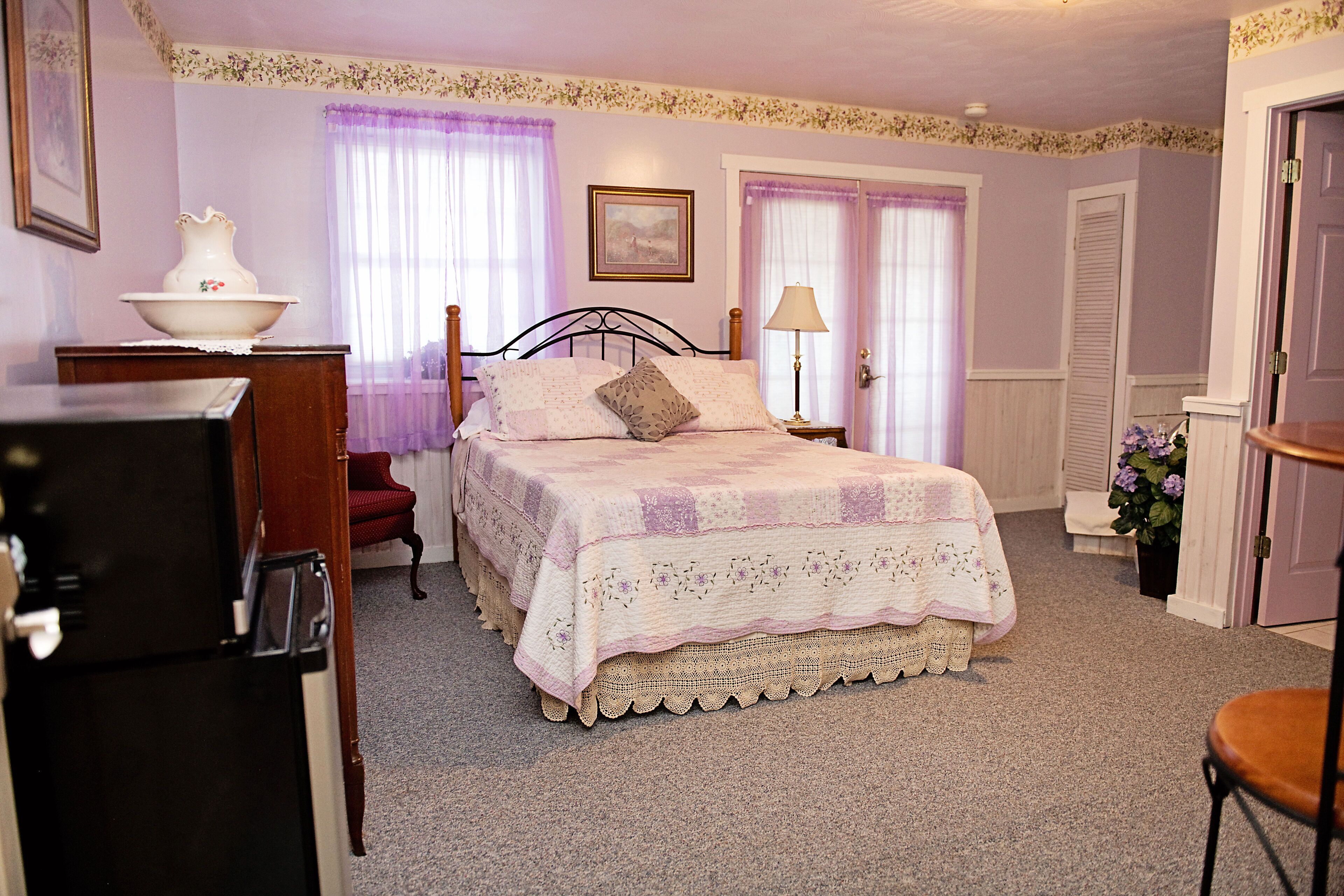 A bedroom with a bed, a dresser, a chair, and a lamp.