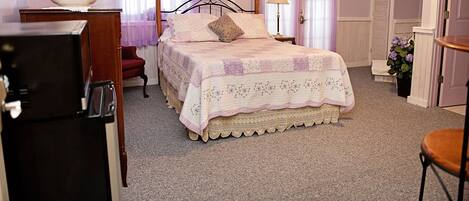 A bedroom with a bed, a dresser, a chair, and a lamp.
