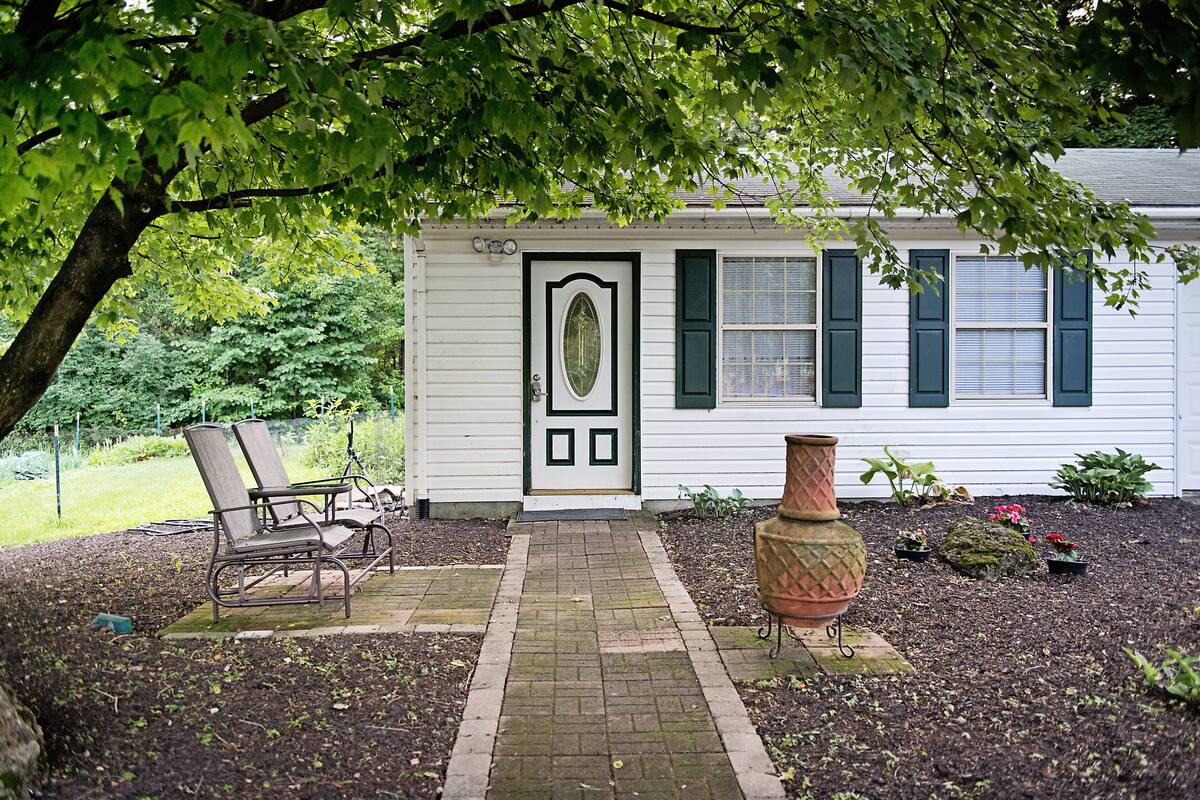 A white house with a front porch, a potted plant, and a chair.