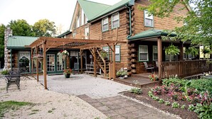 A log cabin with a covered patio, outdoor seating, and a garden.