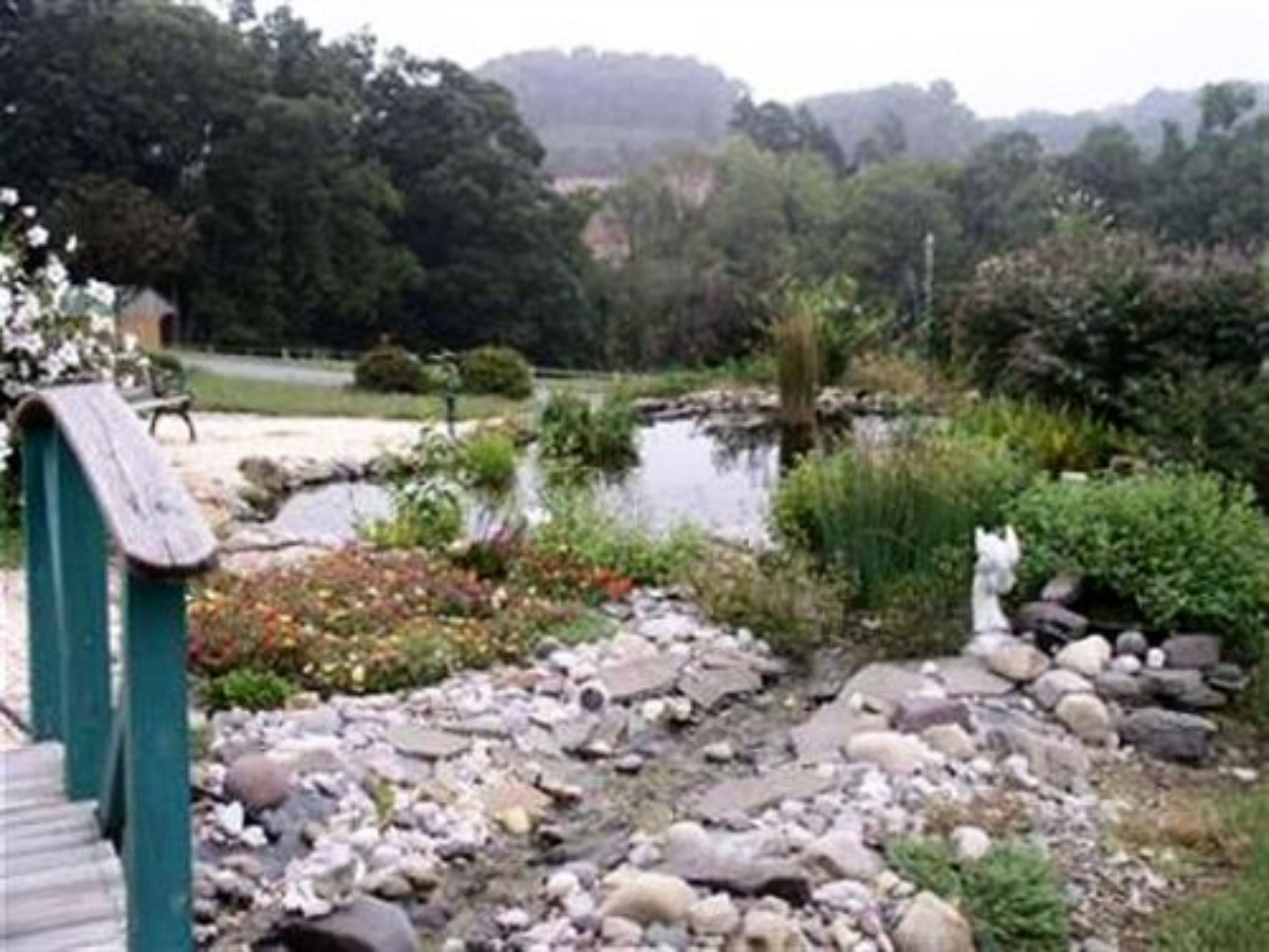 A garden with a pond, rocks, and a wooden bridge.
