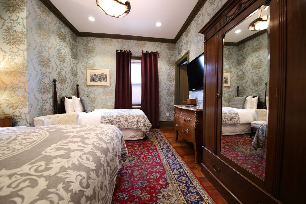 A bedroom with two beds, a dresser, and a mirror.