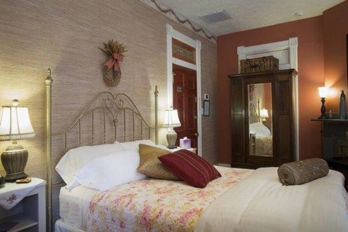 A bedroom with a bed, nightstands, a dresser, and a mirror.