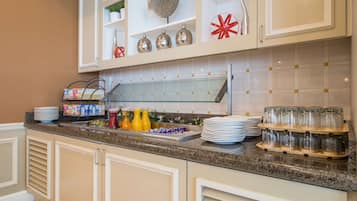 Una cocina con armarios blancos, encimera de granito y vitrina de vidrio.