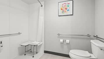 A modern bathroom with a shower, toilet, and a small table with a towel.
