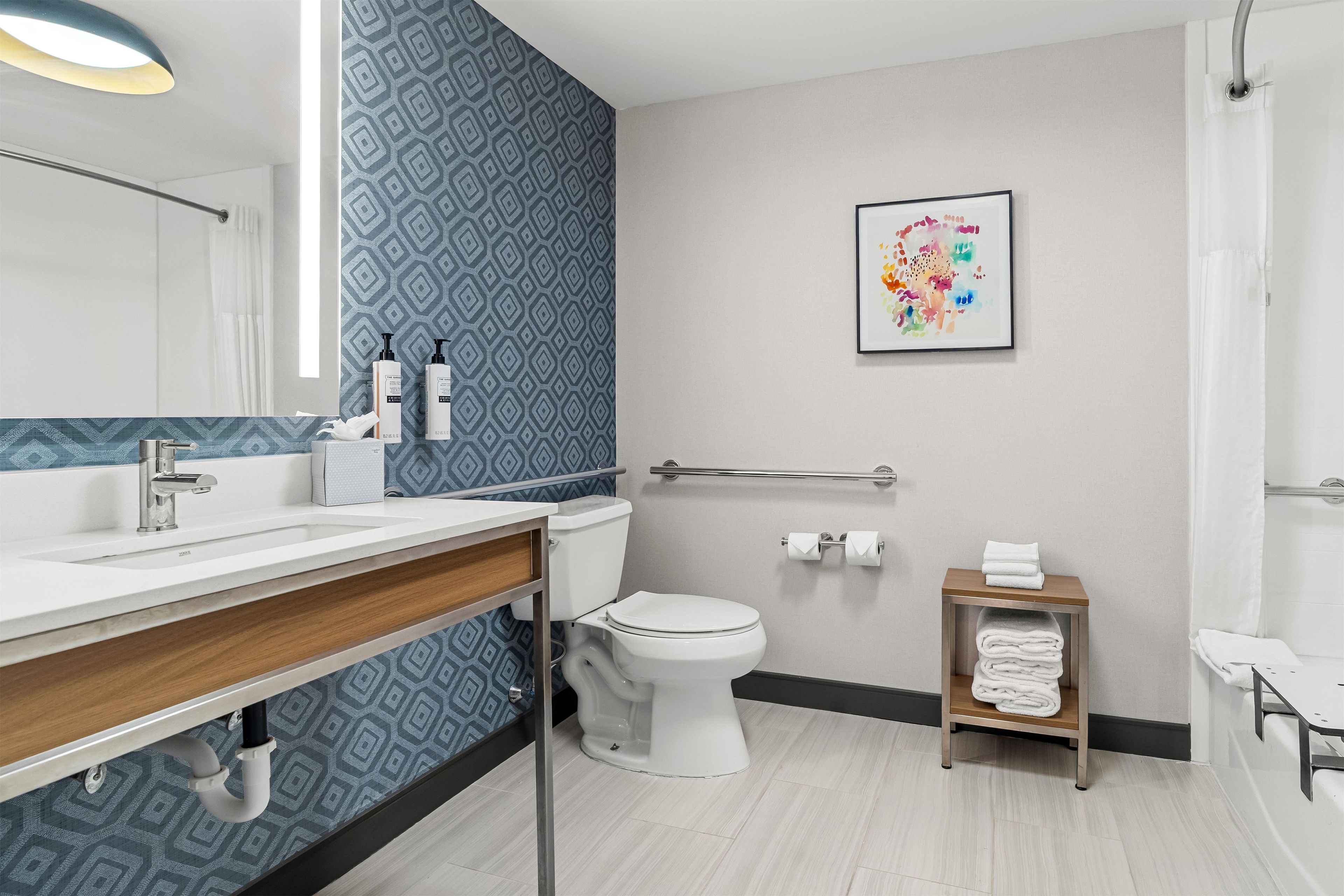 A modern bathroom with a white sink, toilet, and shower area.