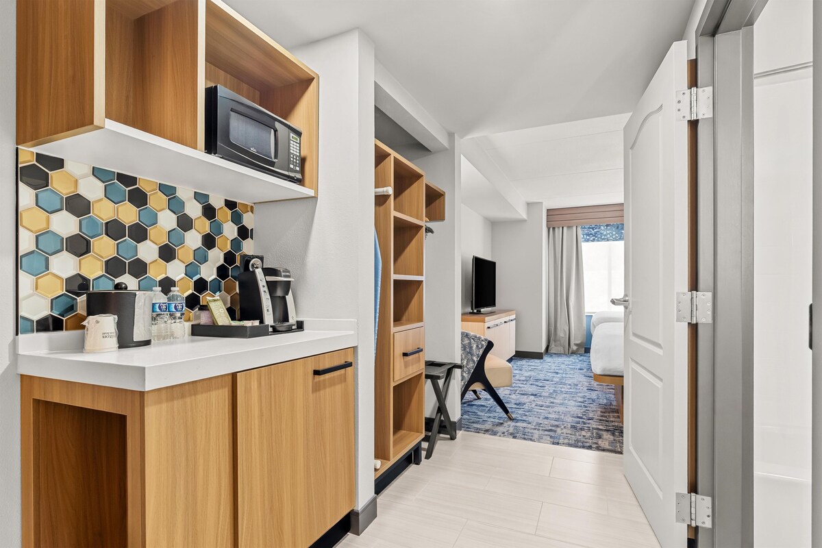 A hotel room with a kitchenette, a microwave, a coffee maker, and a television.
