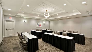 Un salón de conferencias con mesas, sillas y una araña.