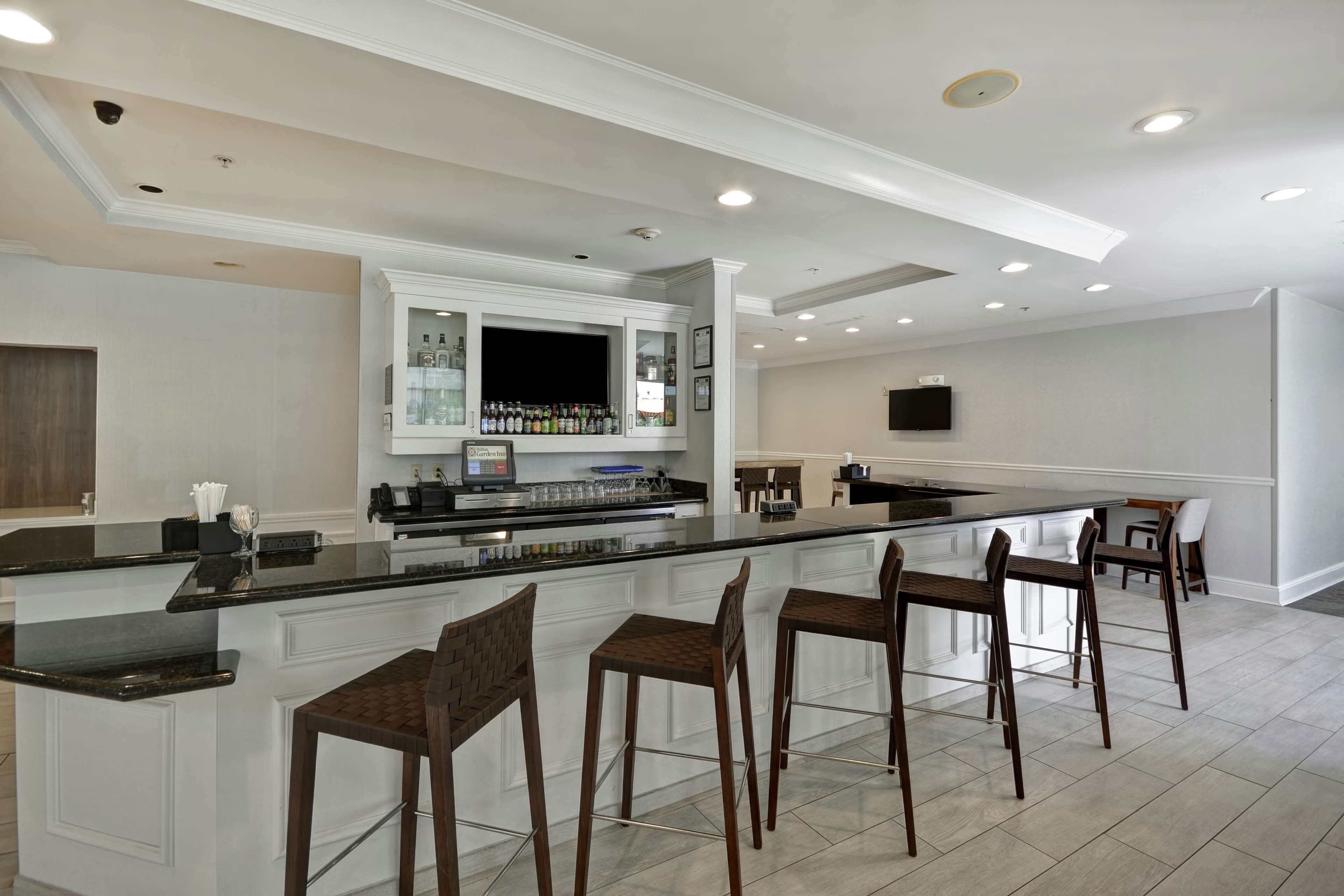 A modern kitchen with a bar area, white cabinetry, and a large island with bar stools.