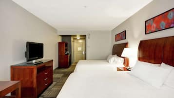 Una habitación de hotel con una cama grande, un televisor sobre un aparador de madera, un escritorio y una lámpara.