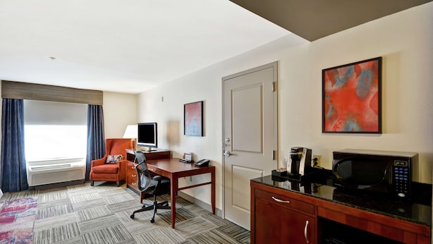 Une chambre d’hôtel équipée d’un bureau, d’une chaise, d’une télévision, d’un four à micro-ondes et d’une machine à café.