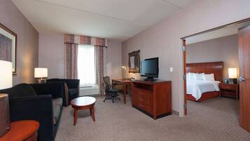A hotel room with a bed, a desk, a chair, a television, and a small table.