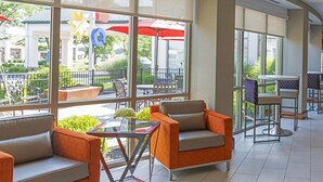 A spacious indoor patio area with comfortable seating, large windows, and a view of the outdoor seating area. - Hilton Garden Inn Columbus/Edinburgh (Edinburgh)