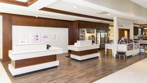 A hotel reception area with a modern design, featuring a reception desk, a counter, and a display of framed artwork. - Hilton Garden Inn Columbus/Edinburgh (Edinburgh)