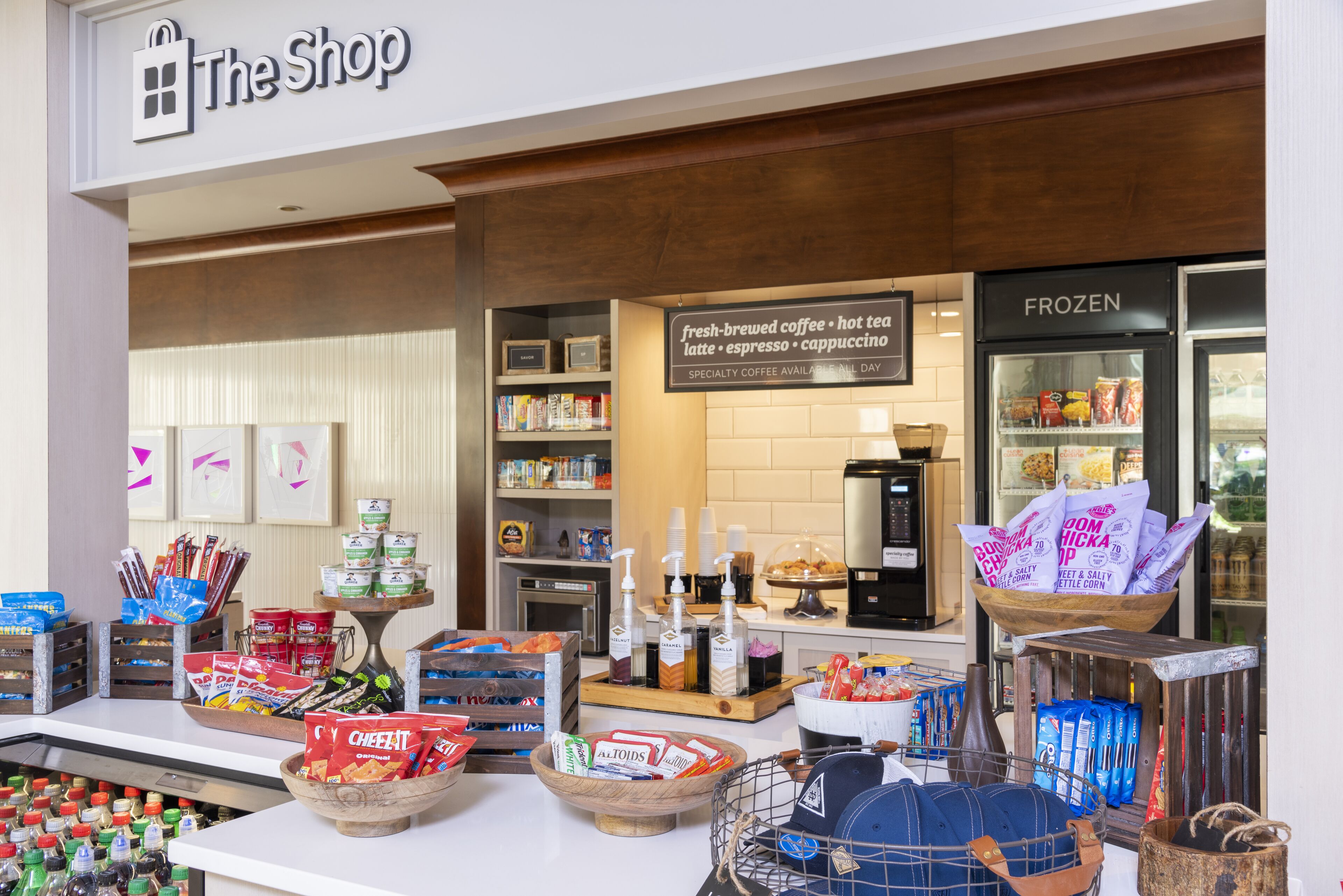 Una cafetería con un letrero que dice "The Shop" y una exhibición de opciones de café y té.