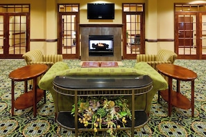 A room with a fireplace, two armchairs, a sofa, a television, and patterned carpet. - Holiday Inn Express & Suites Millington by IHG (Millington)