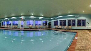 A large indoor swimming pool with lounge chairs and a view of the night sky through large windows. - Holiday Inn Express & Suites Millington by IHG (Millington)