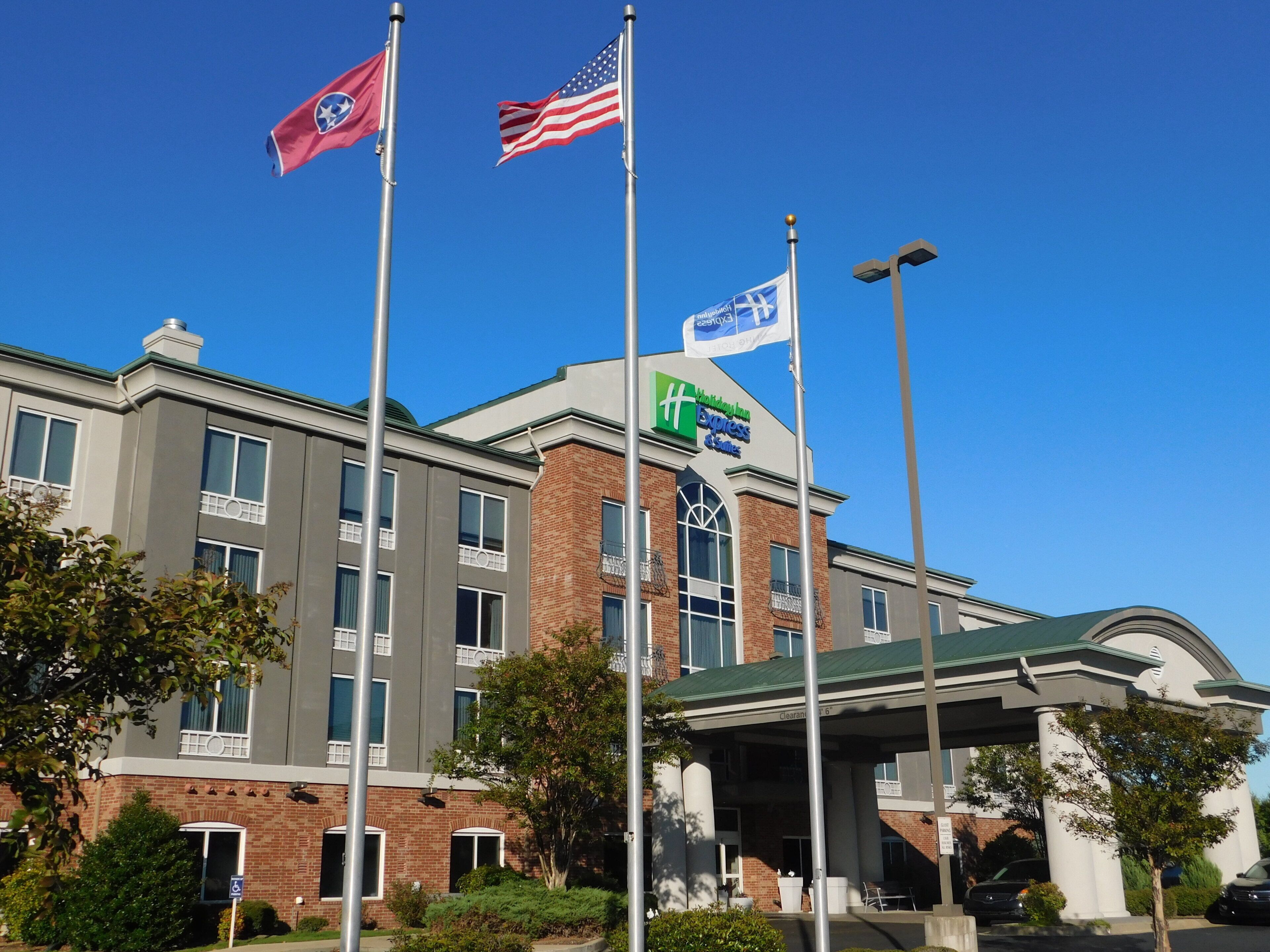 A hotel with a clear sky, multiple flags, and a gas station canopy.