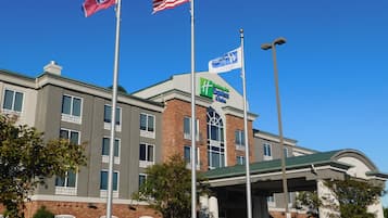 A hotel with a clear sky, multiple flags, and a gas station canopy.