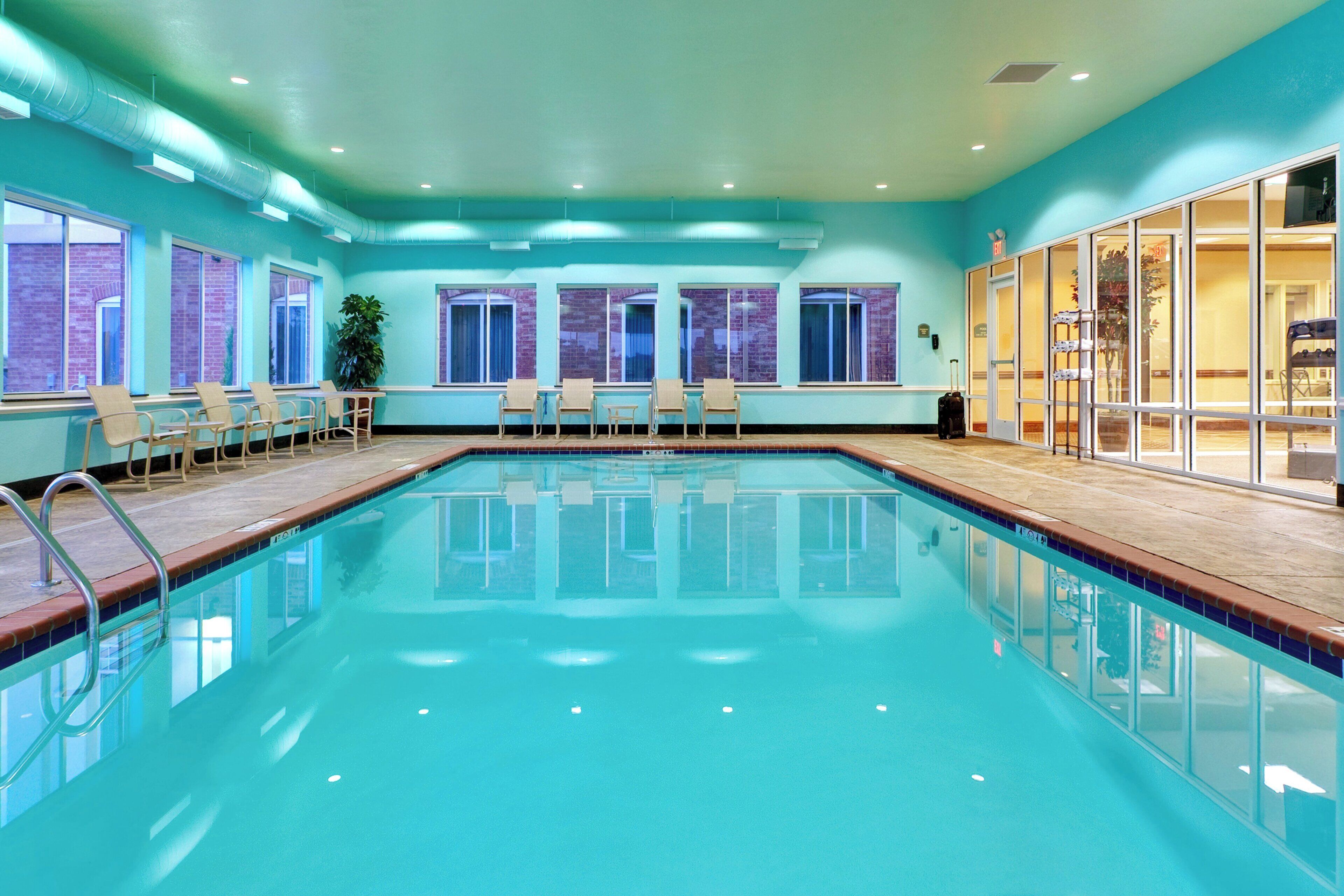 Una piscina con agua cristalina, rodeada de ventanas y sillas.