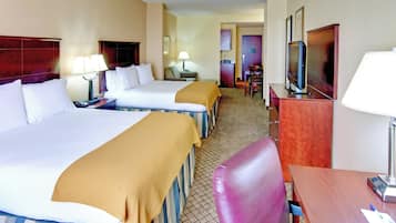 A hotel room with two beds, a desk, a chair, a television, and a bathroom visible in the background.